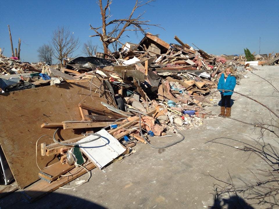 Kylie Lutschg stands next to the remains of the Washington home she shared with her mother. The pair were in the basement when the tornado hit Nov. 17, 2013