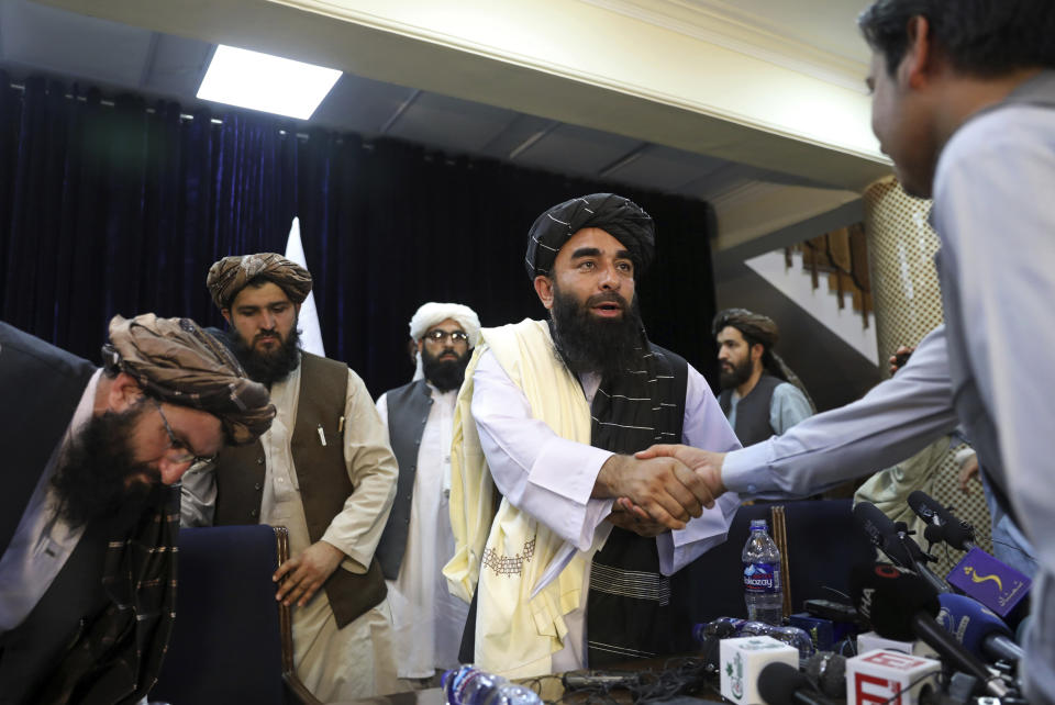 FILE - In this Aug. 17, 2021, file photo, Taliban spokesman Zabihullah Mujahid, shakes hands with a journalist after his first news conference, in Kabul, Afghanistan. Mujahid vowed that the Taliban would respect women's rights, forgive those who resisted them and ensure a secure Afghanistan as part of a publicity blitz aimed at convincing world powers and a fearful population that they have changed. (AP Photo/Rahmat Gul, File)