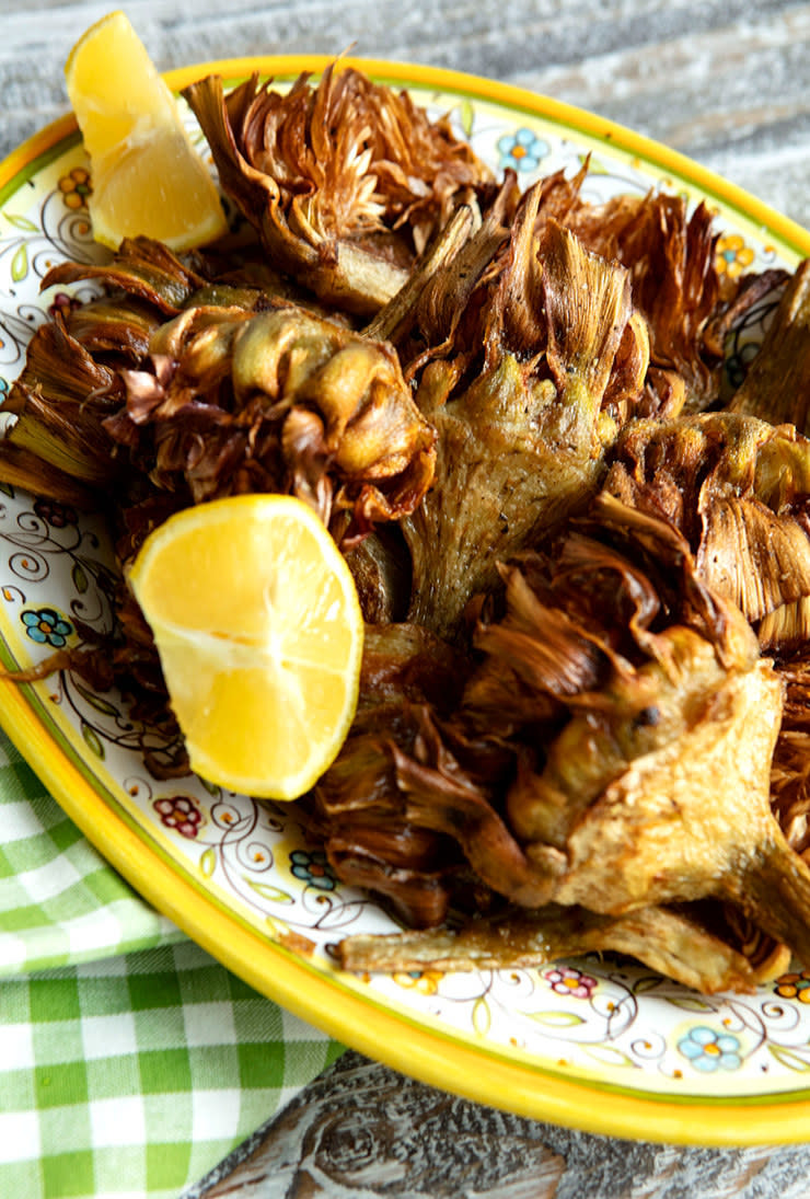 Deep fried artichoke hearts with lemon on a plate.