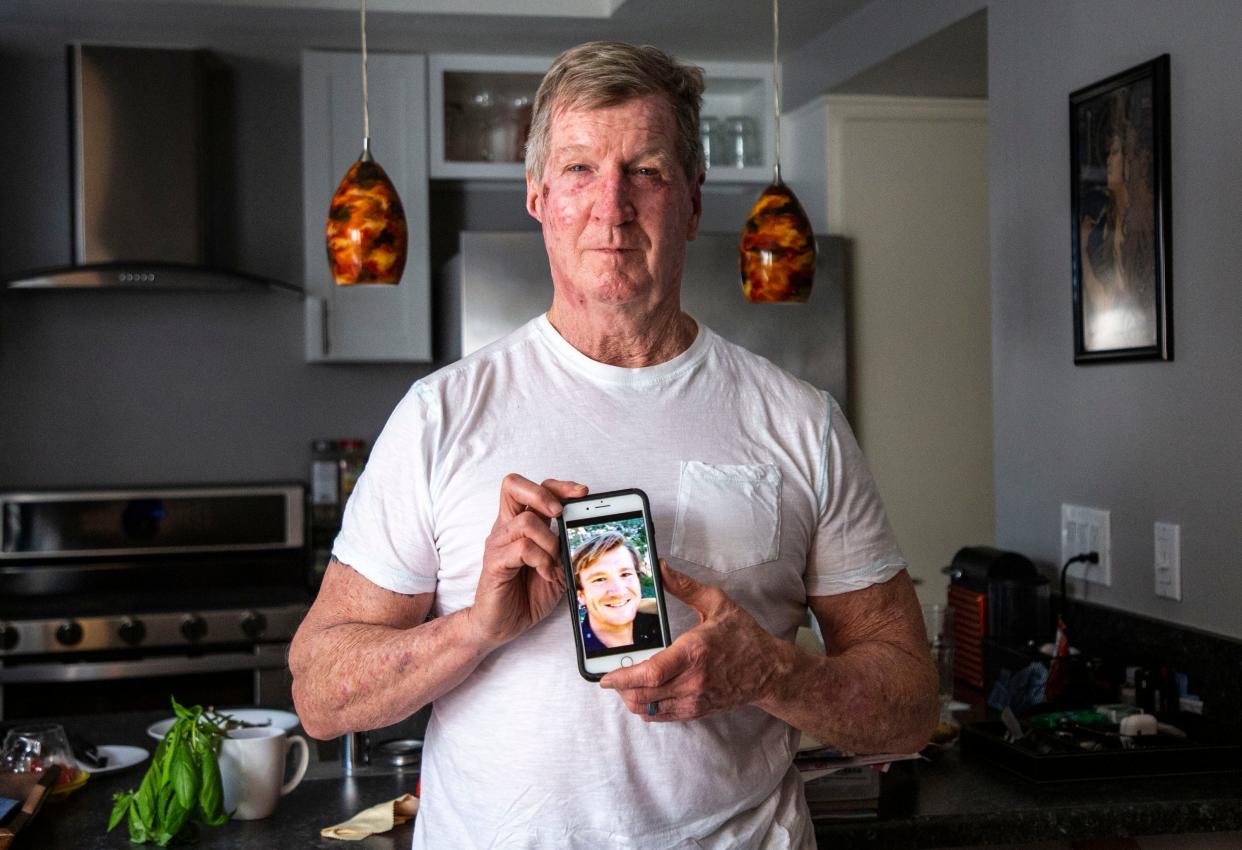 William Spann poses for a photo on Friday, Feb. 11, 2022, while holding a picture of his son, David Spann. William Spann was standing in his condo near where his son was shot to death on April 23, 2021, by Fabian Hector Herrera, a bounty hunter hired by bail agents Spann was in contract with. Spann's family continues to demand justice, including major reforms of the bail industry.