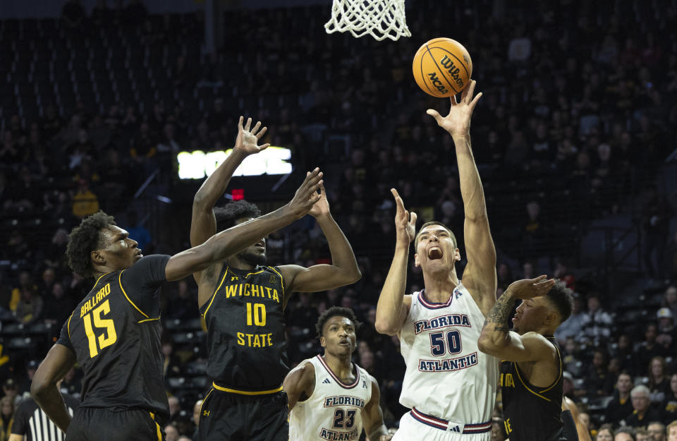 Florida Atlantic's Vladislav Goldin shoots against Wichita State defenders Dalen Ridgnal, middle, and Quincy Ballard, left, during the first half of an NCAA college basketball game on Sunday, Feb., 11, 2024, in Wichita, Kan. (Travis Heying/The Wichita Eagle via AP)