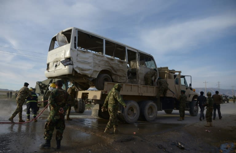 Afghan National Army (ANA) soldiers stand near a bus damaged by a suicide attack in Dehdadi, a district close to the provincial capital Mazar-i-Sharif, on February 8, 2016