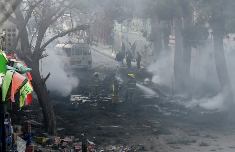 Firefighters work to extinguish a fire at the site of an explosion which struck a bus during rush hour in downtown Kabul on March 13, 2017