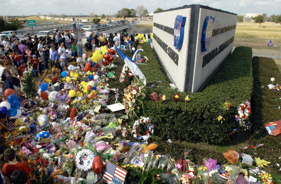 Crowds gather at a makeshift memorial for the crew of the Space Shuttle Columbia February 2, 2003 at NASA's Johnson Space Center in Houston, Texas. (Photo by Brett Coomer/Getty Images)