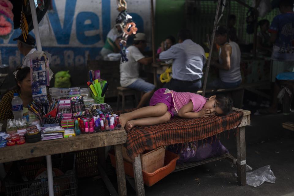 Six-year-old Kiara rests while her mother works selling produce at a street market in the Belen neighborhood of Iquitos, Peru, Saturday, May 25, 2024. The Indigenous community in the heart of Peru's Amazon known as the "Venice of the Jungle" is hosting the Muyuna Floating Film Festival, celebrating tropical forests. (AP Photo/Rodrigo Abd)