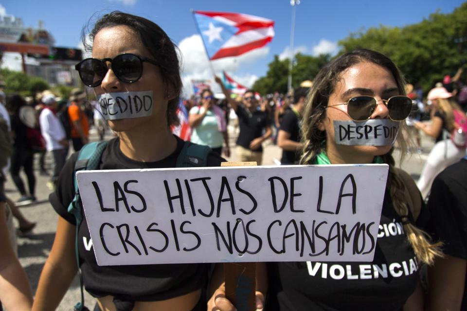 Demonstrators with their mouths covered with a tape and a sign that reads in Spanish "The daughters of the crisis got tired" during a march on Las Americas highway demanding the resignation of governor Ricardo Rossello, in San Juan, Puerto Rico, Monday, July 22, 2019. Protesters are demanding Rossello step down for his involvement in a private chat in which he used profanities to describe an ex-New York City councilwoman and a federal control board overseeing the island's finance. (AP Photo / Dennis M. Rivera Pichardo)