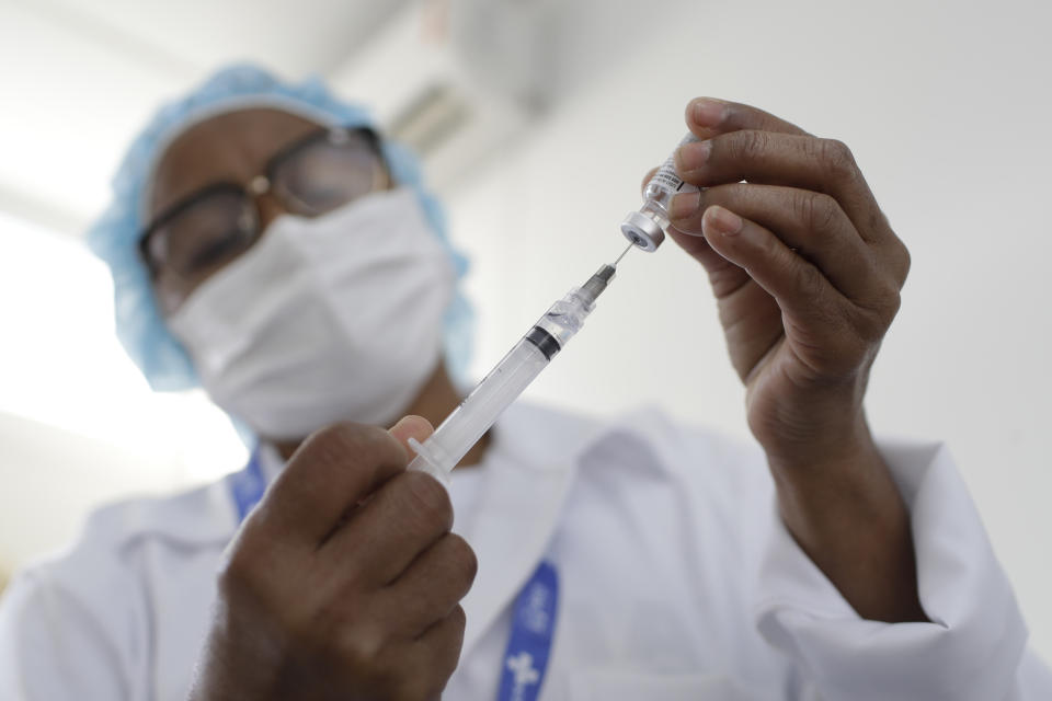 A health worker prepares a shot of the AstraZeneca vaccine on the first day of a three-day COVID-19 vaccination campaign for people over age 35 in the Complexo da Maré favela of Rio de Janeiro, Brazil, Brazil, Thursday, July 29, 2021. Some recipients will be monitored to study the rate of protection the vaccines provide and the extent to which virus variants are circulating. (AP Photo/Bruna Prado)