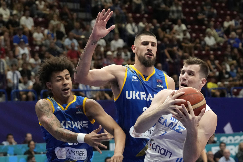 Greece's Dimitrios Agravanis, right, challenges for the ball with Ukraine's Issuf Sanon, left, and Ukraine's Alex Len during their Eurobasket group C basketball match in Milan, Italy, Tuesday, Sept. 6, 2022. (AP Photo/Antonio Calanni)