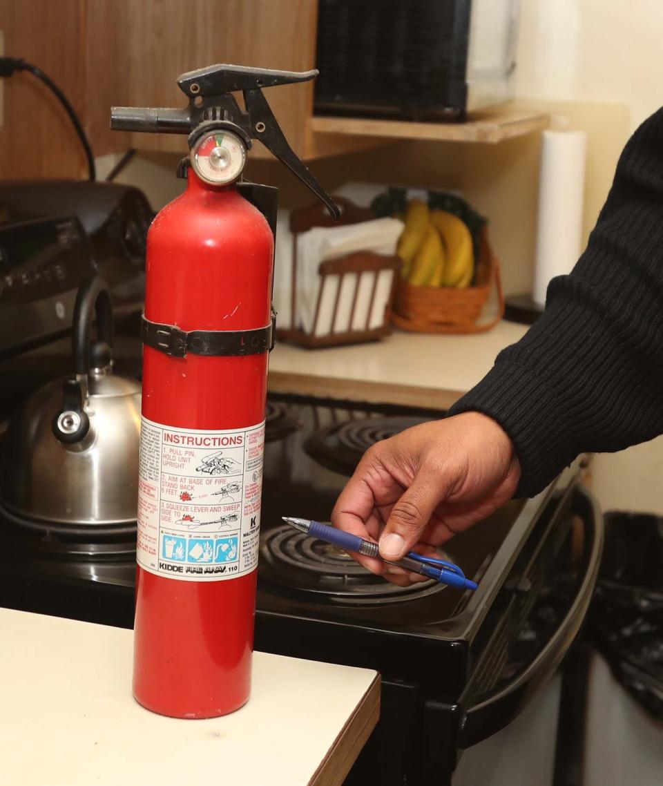 Lt. Thomas A. Whatley of the Akron Fire Department informs a resident that an old fire extinguisher should be replaced during a safety inspection.