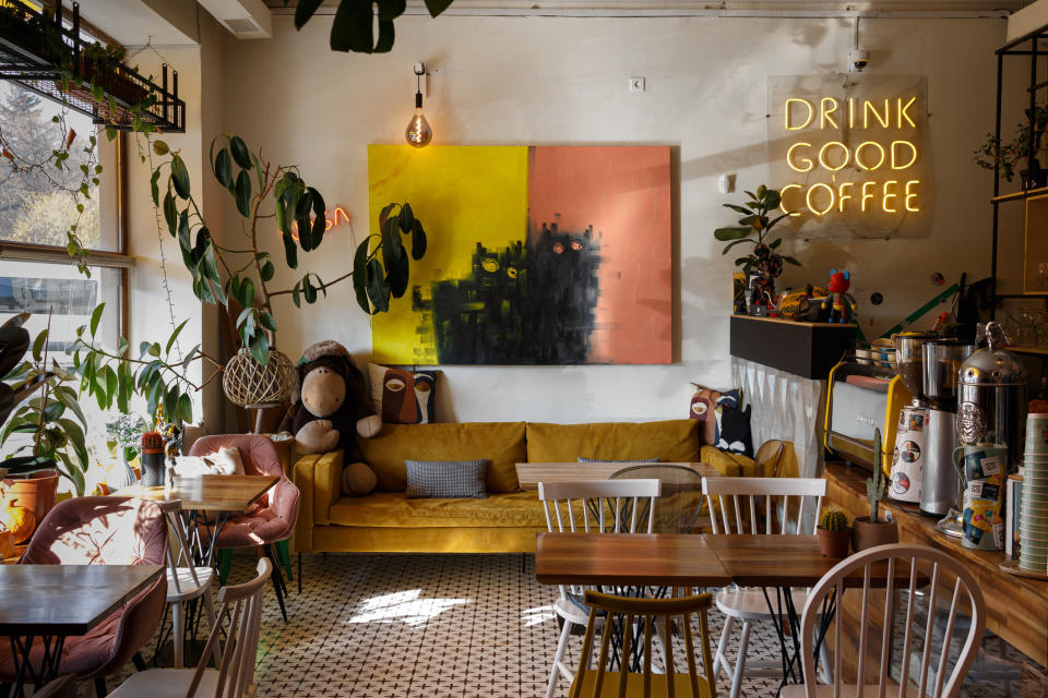 interior of a small coffee shop with a neon light, sofa, and wooden tables