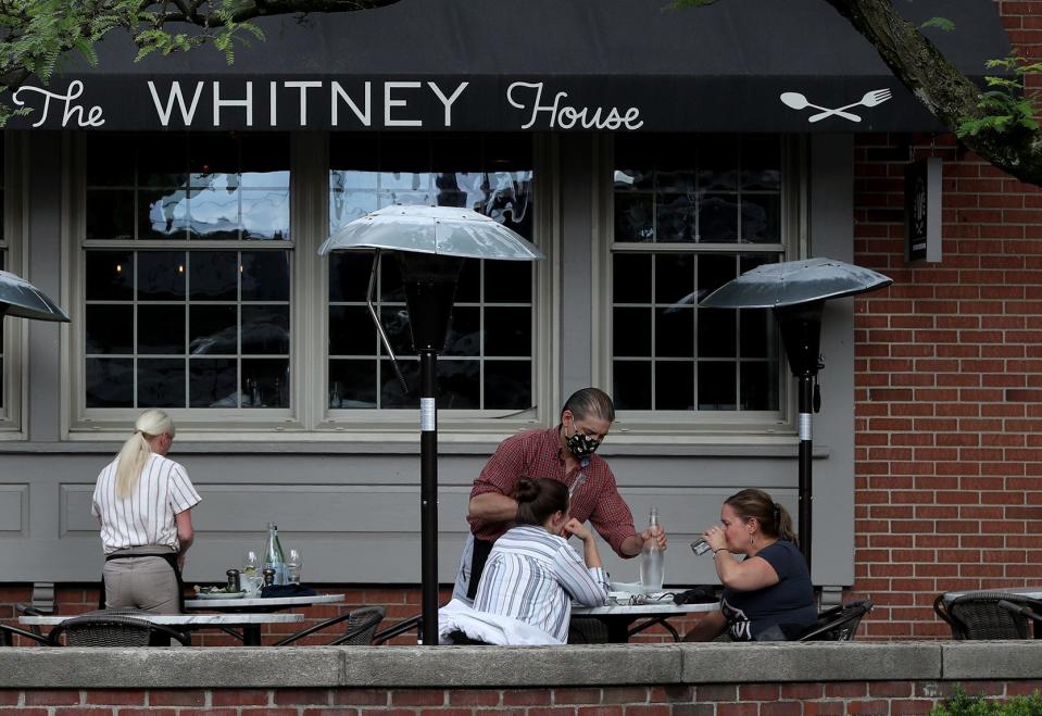 Server Frank Barton brings fresh water to Eliza Berts and Kimberly Gibson, both of Clintonville, on June 9, 2021, at the Whitney House in Worthington. The restaurant is planning to expand its patio.