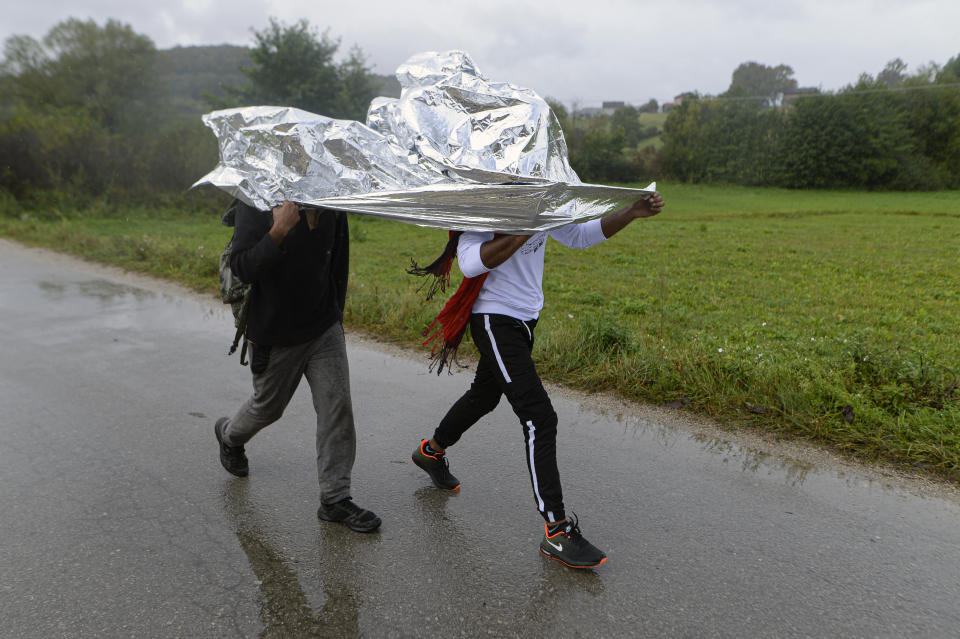 Migrants share thermal sheeting to protect himself from a heavy rain while walking on a road outside Velika Kladusa, Bosnia, Saturday, Sept. 26, 2020.(AP Photo/Kemal Softic)