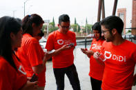 The logo of Chinese ride-hailing firm Didi Chuxing is seen on the t-shirt of employees as they look at the company's app, outside the new drivers center in Toluca, Mexico, April 23, 2018. REUTERS/Carlos Jasso