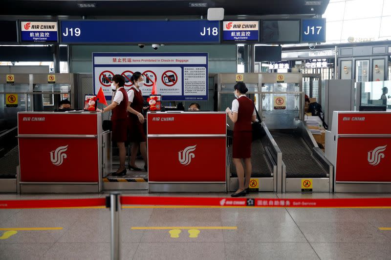 Staff members wearing face masks are seen at counters at Beijing Capital International Airport