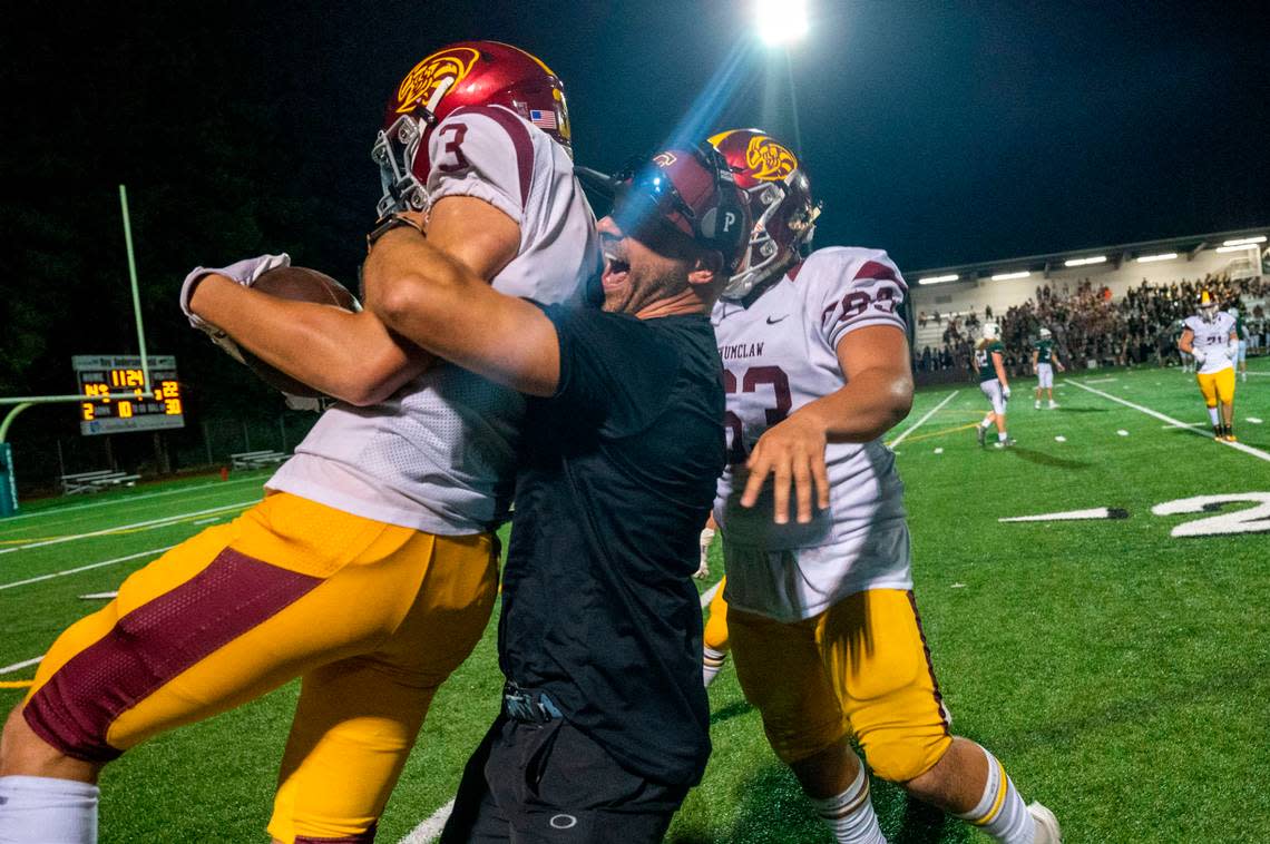 Enumclaw head coach Mark Gunderson hugs defensive back Westin Triplett after his fourth-quarter interception on a pass by Peninsula Payton Knowles during a nonleague game on Thursday, Sept. 1, 2022, at Roy Anderson Field in Gig Harbor Wash.