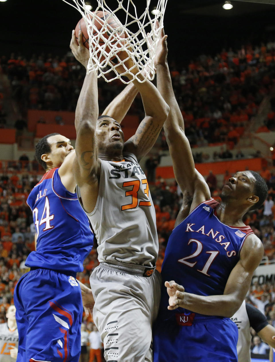 Oklahoma State guard Marcus Smart (33) shoots between Kansas forward Perry Ellis (34) and center Joel Embiid (21) during the second half of an NCAA college basketball game in Stillwater, Okla., Saturday, March 1, 2014. Oklahoma State won 72-65. (AP Photo/Sue Ogrocki)