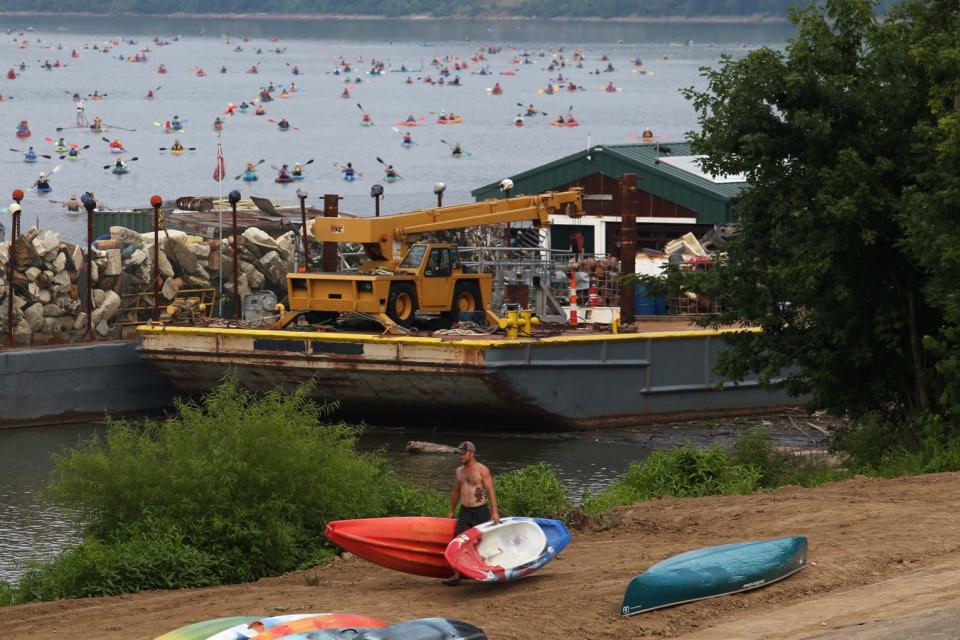 A man walks along the shore of the Ohio River while people begin kayaking and canoeing during Paddlefest in 2021.