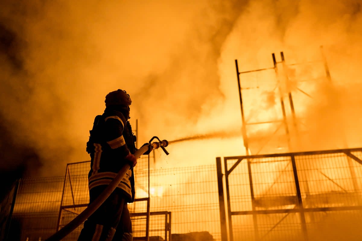 A firefighter tackles a blaze at a shopping centre in Kherson following a Russian missile strike  (AP)