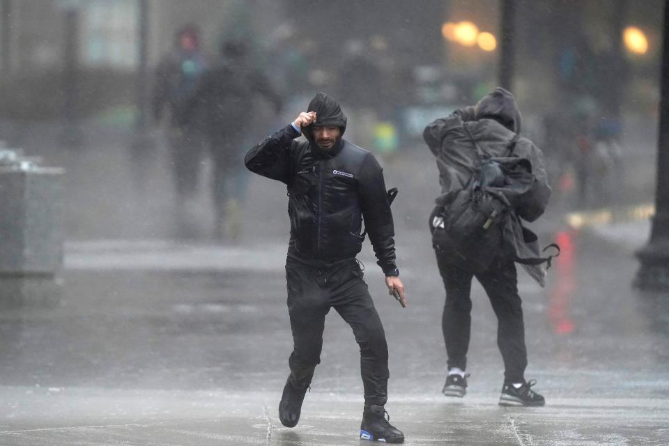 Pedestrians are buffeted by wind and rain as they cross a street, Monday, Dec. 18, 2023, in Boston. A storm moving up the East Coast brought heavy rain and high winds to the Northeast on Monday, threatening flooding, knocking out power to hundreds of thousands. (AP Photo/Steven Senne)