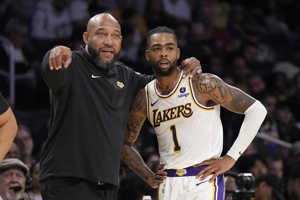 Lakers coach Darvin Ham, left, talks with guard D'Angelo Russell along the sideline during a preseason game against the Bucks