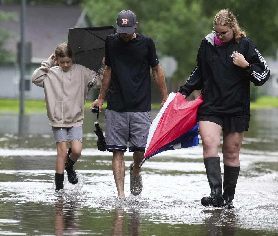 Amanda Kovar, right, walks with her husband, Matthew, and daughter, Zoe, through their neighborhood in North Woodland Hills after severe flooding, Thursday, May 2, 2024, in the Houston neighborhood of Kingwood, Texas. (Jason Fochtman/Houston Chronicle via AP)