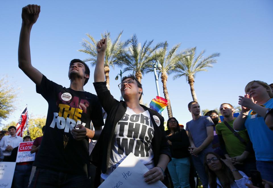 Anthony Musa, left, and Brianna Pantillione join nearly 250 gay rights supporters protesting SB1062 at the Arizona Capitol, Friday, Feb. 21, 2014, in Phoenix. The protesters gathered demanding Gov. Jan Brewer veto legislation that would allow business owners to refuse to serve gays by citing their religious beliefs. The governor must sign or veto Senate Bill 1062 by the end of next week. (AP Photo/Ross D. Franklin)