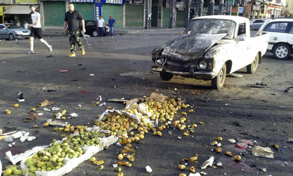 In this photo released by the Syrian official news agency SANA, Syrians inspect the site of a suicide attack in Sweida, Syria, Wednesday, July 25, 2018. Syrian state media say dozens of people have been killed in a suicide attack in the country's south, blaming the bombing on Islamic State militants. (SANA via AP)