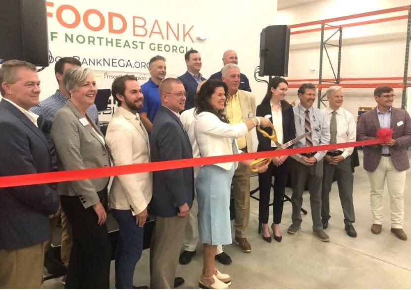 Erin Barger, president and CEO of the Food Bank of Northeast Georgia, holds scissors for ribbon cutting Thursday.