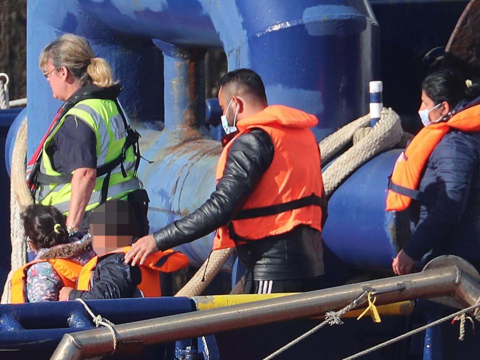 A Border Force officer escorts a young family thought to be migrants from a Border Force vessel at Dover, Kent: PA