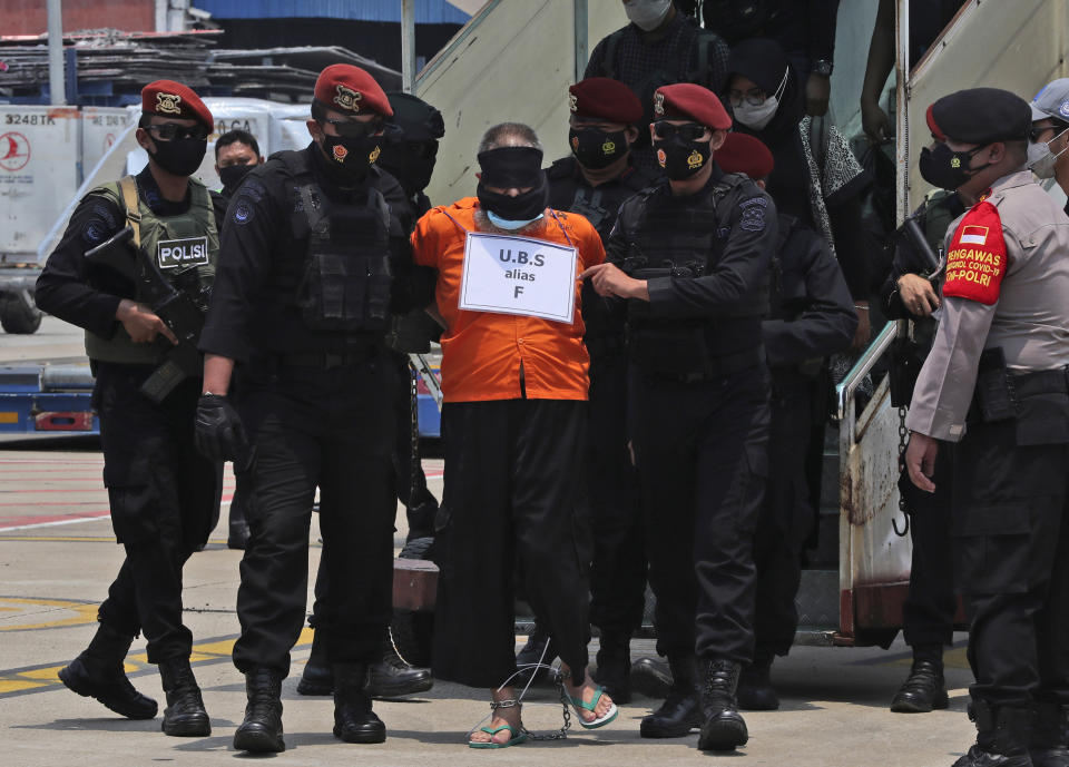 Police escort Usman bin Sef, also known as Fahim, a convicted leader of al-Qaida-linked Jemaah Islamiyah extremist group in East Java province, upon arrival at the Soekarno-Hatta International Airport in Tangerang, Indonesia, Thursday, March 18, 2021. Indonesian authorities on Thursday transferred suspected militants arrested in raids in the last few weeks, from East Java to the capital city for further questioning. (AP Photo/Achmad Ibrahim)