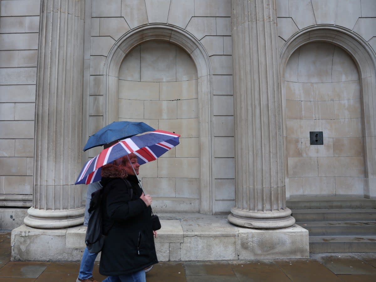 File: Tourists shelter from the rain under an Union Jack umbrella near the Bank of England in the City of London financial district in London, Britain, 13 February 2024 (REUTERS)