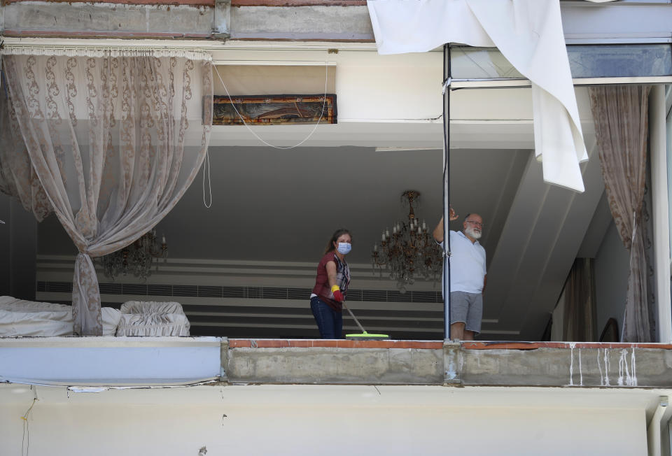 A woman cleans debris from her damaged apartment a day after an explosion hit the seaport of Beirut, Lebanon, Wednesday, Aug. 5, 2020. Residents of Beirut confronted a scene of utter devastation on Wednesday, a day after a massive explosion at the port rippled across the Lebanese capital, killing at least 100 people, wounding thousands and leaving entire city blocks flooded with glass and rubble. (AP Photo/Hussein Malla)