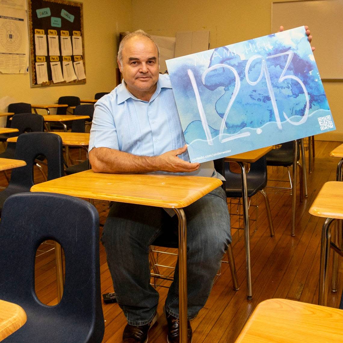 Cuban artist Xavier Cortada holds up a yard sign marked with the elevation of Miami Senior High in Miami on Tuesday, April 5, 2022. The eco project dubbed ‘The Underwater’ allows high school kids to learn about their homes’ elevation above sea level and then asks them to plant yard signs with the marked elevation in their own yards in an effort to catalyze conversation and action around the climate crisis.