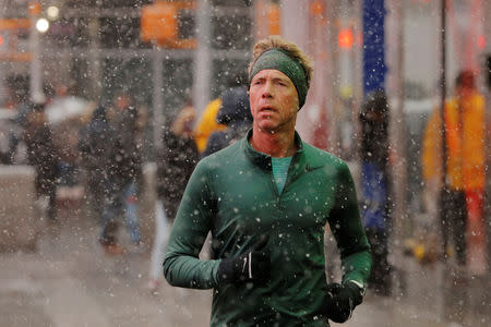 A runner jogs down the sidewalk as snow falls in the Times Square neighborhood of New York, U.S., February 12, 2019. REUTERS/Lucas Jackson