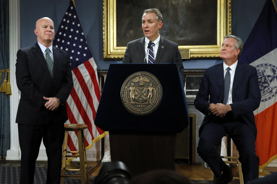 New York City Police Commissioner James O'Neill, left, listens as his successor, Chief of Detectives Dermot Shea, center, speaks at New York City Hall, while New York Mayor Bill de Blasio looks on, Monday, Nov. 4, 2019. New York City's police commissioner is retiring after three years in charge of the nation's largest police department, Mayor Bill de Blasio said Monday. (AP Photo/Richard Drew)