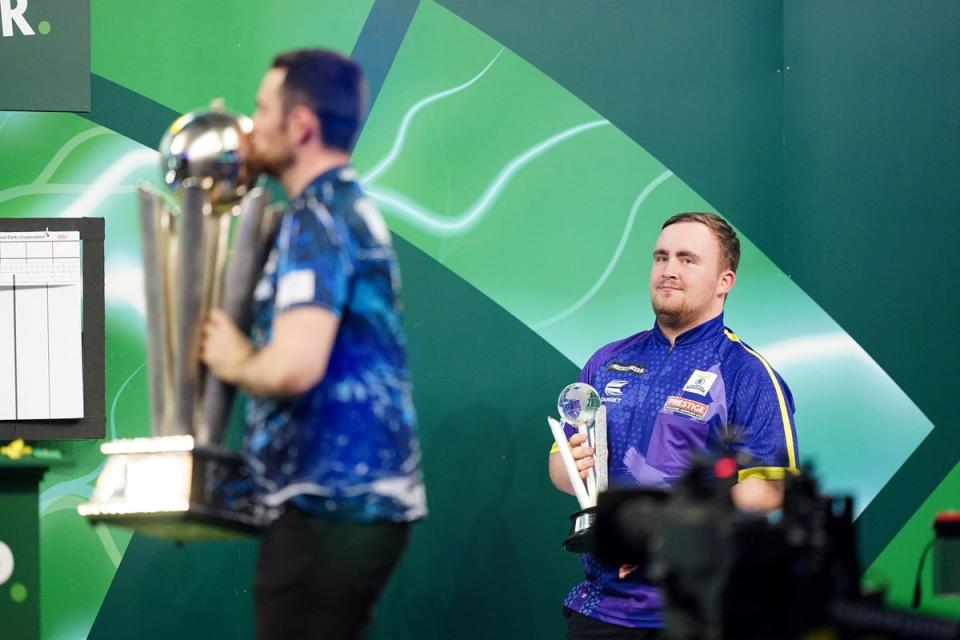 Littler looks on as Luke Humphries celebrates with the trophy (PA)