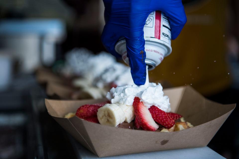 The Waffle Lab's Amelia Brull garnishes a row of "The European" waffles during the first day of Taste of Fort Collins on Friday, June 7, 2019, in Fort Collins, Colo. 