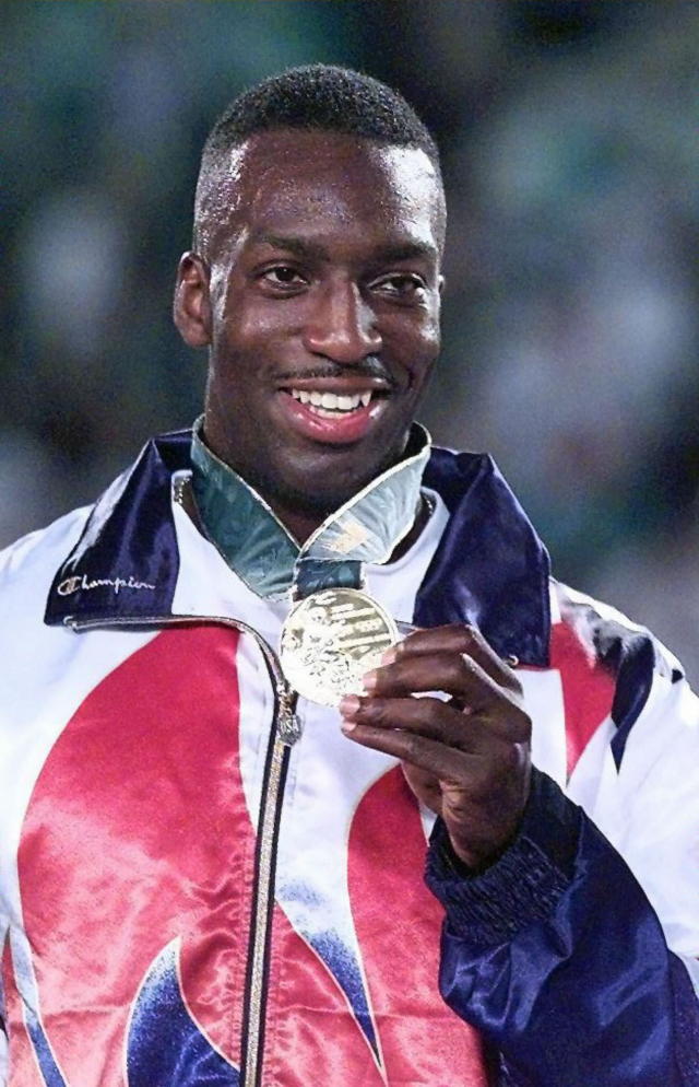 Michael Johnson of the US displays the gold medal he received for winning the men's 400m late 29 July 1996 on the podium at the Olympic Stadium in Atlanta. Michael Johnson won gold in 43.49 sec, an Olympic record, but missed the world mark by two tenths of a second. (FOR EDITORIAL USE ONLY) AFP-IOPP/Don EMMERT