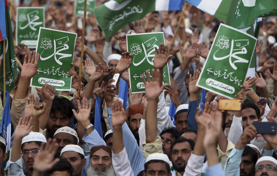 Supporters of Jamaat-i-Islami, a Pakistani Islamist party, raise their hands and hold placards that read, "Ready to die for Muhammad" at a rally to condemn a Supreme Court decision that acquitted Asia Bibi, a Christian woman, who spent eight year on death row accused of blasphemy, in Karachi, Pakistan, Sunday, Nov. 4, 2018. Pakistan's top court acquitted Bibi on Wednesday in a move that infuriated hard-line Islamists, who held three days of nationwide protests demanding her execution. The Islamists ended the protests after the government agreed to impose a travel ban on Bibi and to allow her case to be reviewed. (AP Photo/Fareed Khan)