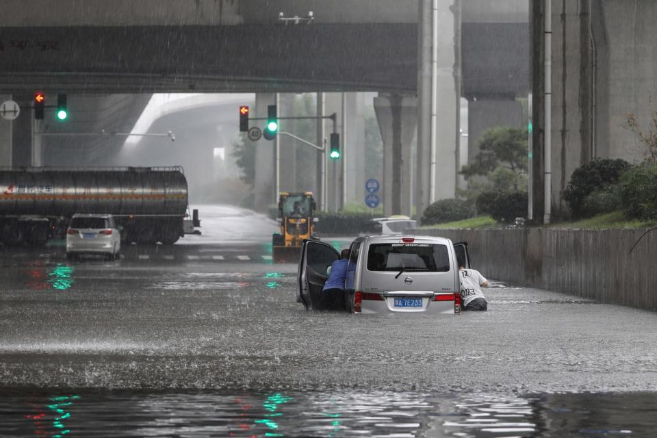 <span>Personas empujando una camioneta a través de una calle inundada luego de las fuertes lluvias en Zhengzhou, en la provincia china de Henan, el 20 de julio de 2021</span><div><span>STR</span><span>AFP</span></div>