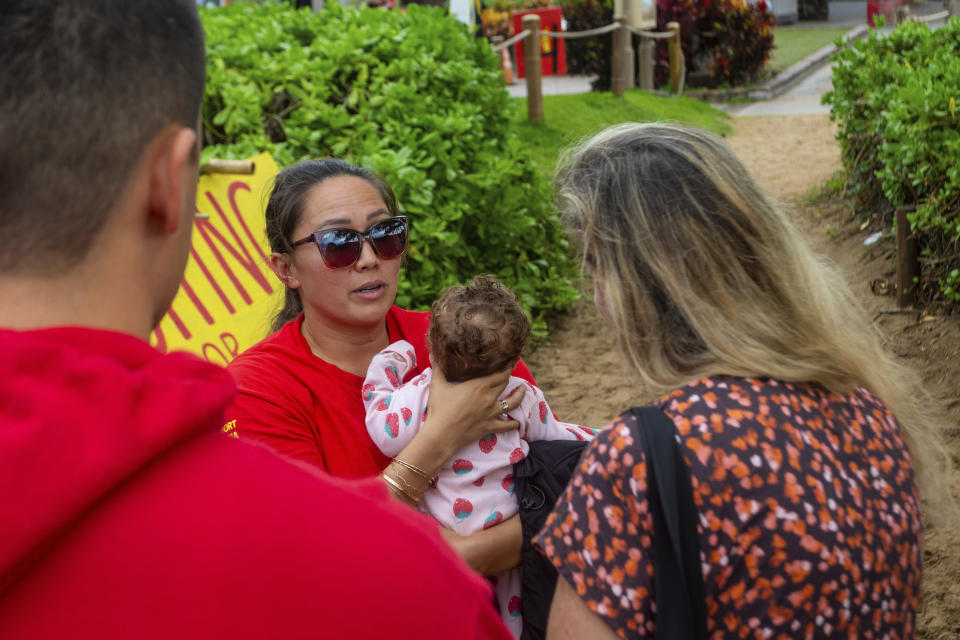 Jordan Ruidas holds her daughter as she speaks with visitors on Friday, Dec. 1, 2023, in Lahaina, Hawaii. Lahaina Strong has set up a "Fish-in" to protest living accommodations for those displaced by the Aug. 8, 2023 wildfire, the deadliest U.S. wildfire in more than a century. More than four months after the fire, tensions are growing between those who want to welcome tourists back to provide jobs and those who feel the town isn't ready for a return to tourism." (AP Photo/Ty O'Neil)