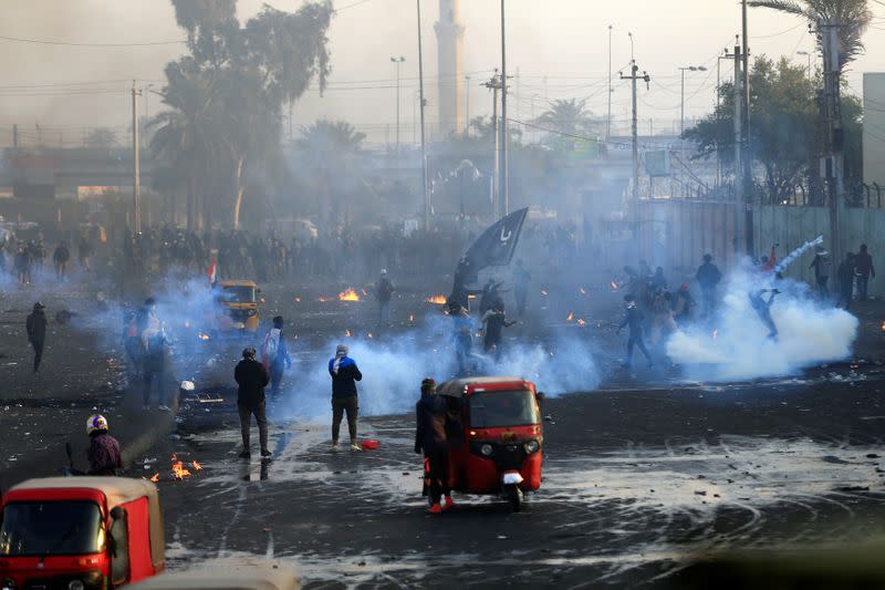 Iraqi demonstrators throw tear gas toward Iraqi security forces during ongoing anti-government protests in Baghdad