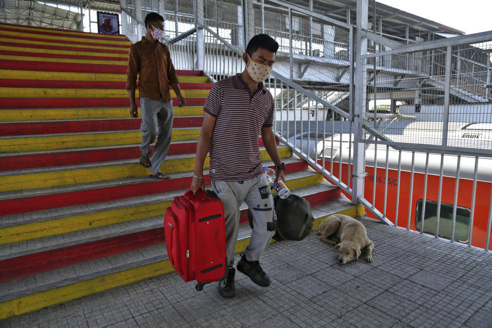 Indian passengers wearing a masks arrive at a railway station in Jammu, India, Monday, March 23, 2020. Authorities have gradually started to shutdown much of the country of 1.3 billion people to contain the outbreak. For most people, the new coronavirus causes only mild or moderate symptoms. For some it can cause more severe illness. (AP Photo/Channi Anand)