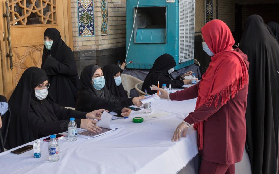 A woman collects her ballot to vote in the presidential electin at a polling station set up in a mosque in Tehran. - Sam Tarling/Sam Tarling for The Telegraph