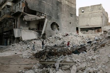 Boys make their way through the rubble of damaged buildings in the rebel held area of al-Kalaseh neighbourhood of Aleppo, Syria, September 29, 2016. REUTERS/Abdalrhman Ismail