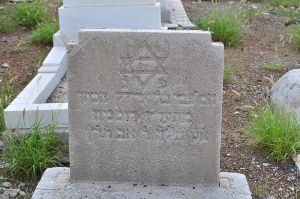 In this Nov. 12, 2012 photo, a headstone stands in the Beth Haim cemetery in Blenheim on the outskirts of Willemstad, Curacao. Beth Haim, believed to be one of the oldest Jewish cemeteries in the Western Hemisphere, established in the 1950s and considered an important landmark on an island where the historic downtown has been designated a UNESCO World Heritage Site, is slowly fading in the Caribbean sun. Headstones are pockmarked with their inscriptions faded, stone slabs that have covered tombs in some cases for hundreds of years are crumbling into the soil, marble that was once white is now grey, likely from the acrid smoke that spews from the oil refinery that looms nearby. (AP Photo/Karen Attiah)