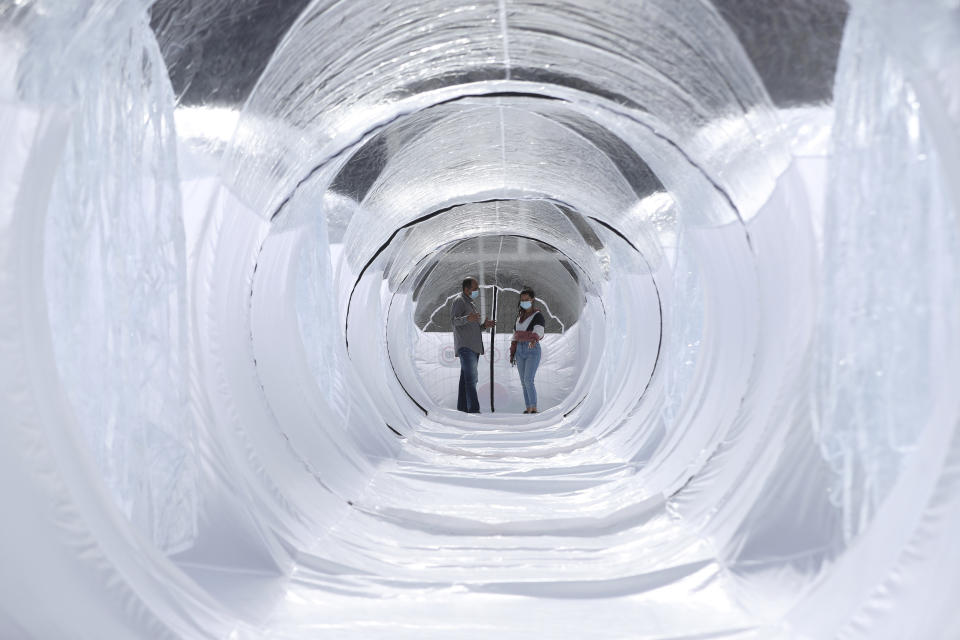 Designers stand inside a Portable Epidemiological Insulation Unit during a media presentation, in Bogota, Colombia, Tuesday, Feb. 16, 2021. Colombia’s La Salle University school of architecture designed the small polyhedral pneumatic geodesic domes which can be used to isolate and treat COVID-19 patients in areas where there are no nearby hospitals or where existing hospitals are overwhelmed with patients. (AP Photo/Fernando Vergara)