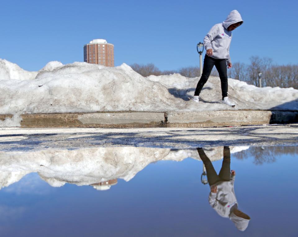 Lana Jones, 9, of Milwaukee is reflected in a puddle of melting snow while playing at Gordon Park on East Locust Street in Milwaukee on Saturday, Feb. 27. She was with her mother, Alecia Jones.