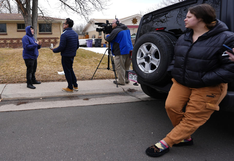 Crystallyn Nunez, back left, talks to a news crew as a friend looks on near a residence where a former funeral home owner kept a deceased women's body in a hearse for two years as well as the remains of 30 cremated people Friday, Feb. 16, 2024, in southwest Denver. The Nunez family contracted with the funeral home owner to cremate two relatives at a cost of $30,000. The discovery occurred on Feb. 6 during a court-ordered eviction of the home rented by 33-year-old Miles Harford, who authorities have issued an arrest warrant for. (AP Photo/David Zalubowski)