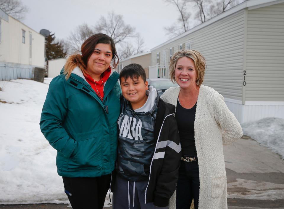 Christine Rodriguez, left, poses for a photo with her 11-year-old son, Oscar Rodriguez, Jr., and their real estate agent, Tiffany Ehler, outside of the mobile home the Rodriguez family currently lives in outside of Des Moines, Iowa, on Sunday, Feb. 1, 2022. 